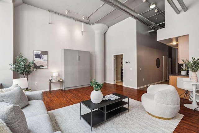 living area with baseboards, a high ceiling, and wood finished floors