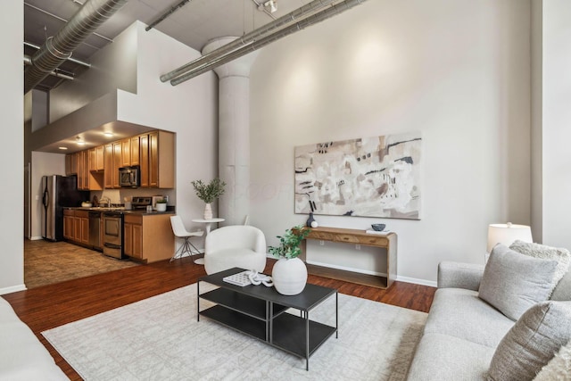 living room with baseboards, wood finished floors, and a towering ceiling