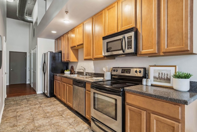 kitchen with dark stone counters, baseboards, appliances with stainless steel finishes, and a sink
