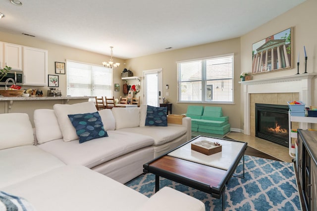 living room featuring a chandelier, plenty of natural light, visible vents, and a fireplace