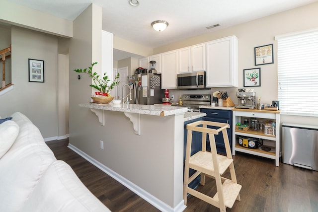 kitchen with visible vents, a peninsula, a breakfast bar area, white cabinetry, and stainless steel appliances