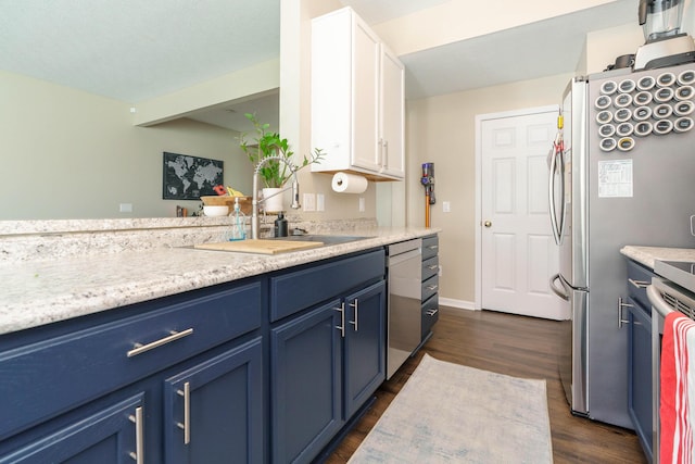 kitchen featuring white cabinets, blue cabinetry, dark wood finished floors, and light countertops