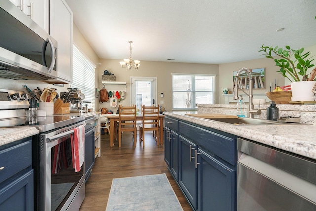 kitchen with an inviting chandelier, light countertops, stainless steel appliances, a sink, and blue cabinetry