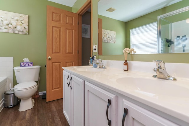 bathroom with double vanity, visible vents, wood finished floors, a sink, and toilet