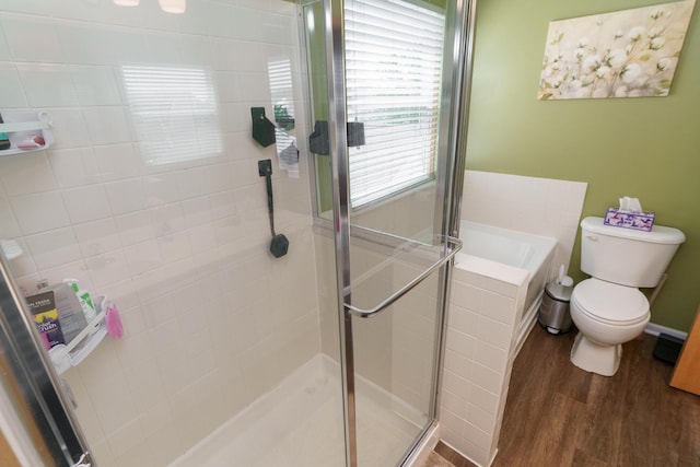 bathroom with a garden tub, a stall shower, toilet, and wood finished floors