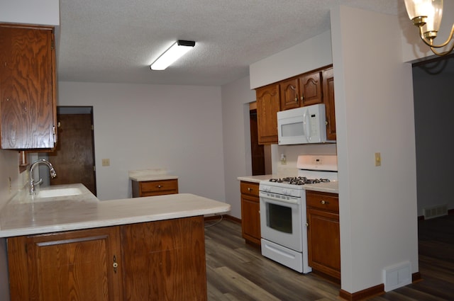 kitchen featuring visible vents, a sink, dark wood-style floors, and white appliances
