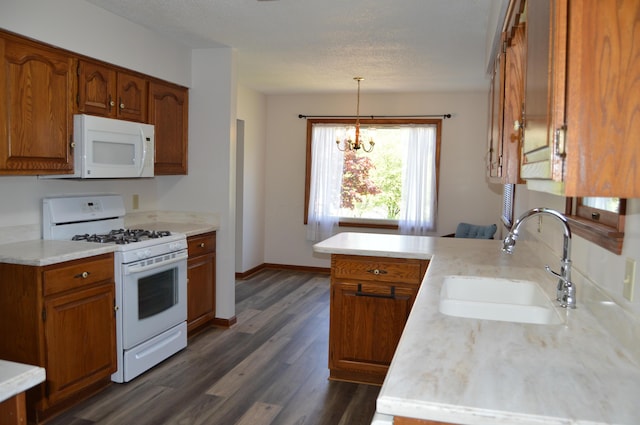 kitchen with brown cabinets, a sink, white appliances, light countertops, and a peninsula