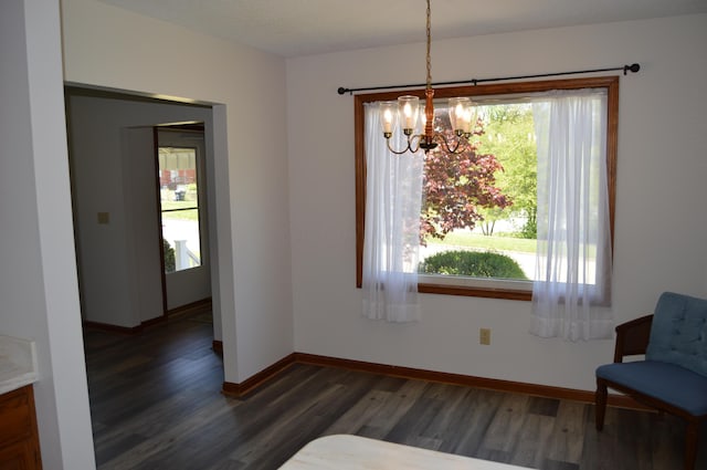 unfurnished dining area featuring an inviting chandelier, baseboards, and wood finished floors