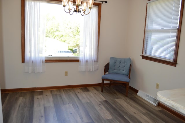 living area with a chandelier, visible vents, plenty of natural light, and wood finished floors
