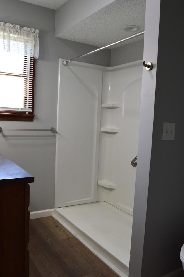 bathroom with a shower, a textured ceiling, toilet, and wood finished floors