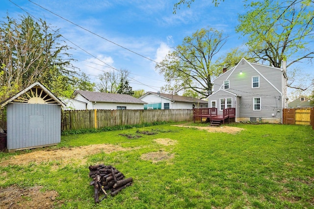 view of yard with a storage unit, a fenced backyard, a wooden deck, and an outdoor structure