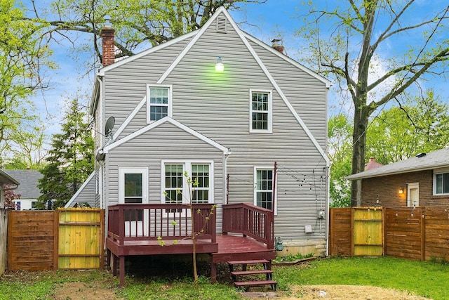 rear view of house featuring a chimney, a gate, a fenced backyard, and a wooden deck