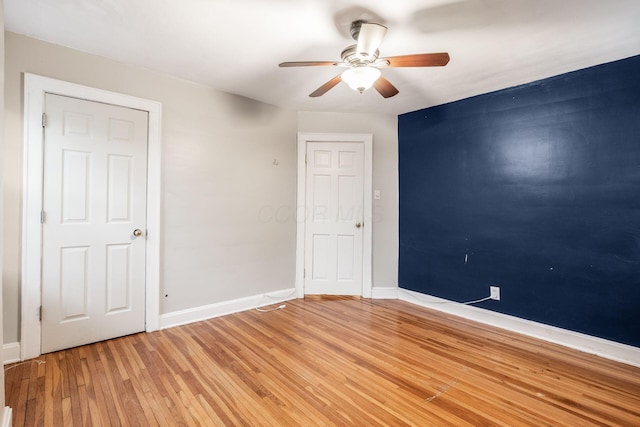 spare room featuring ceiling fan, baseboards, and light wood-style floors