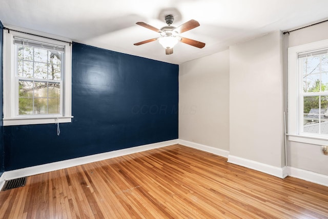 unfurnished room with baseboards, visible vents, ceiling fan, and light wood-style floors