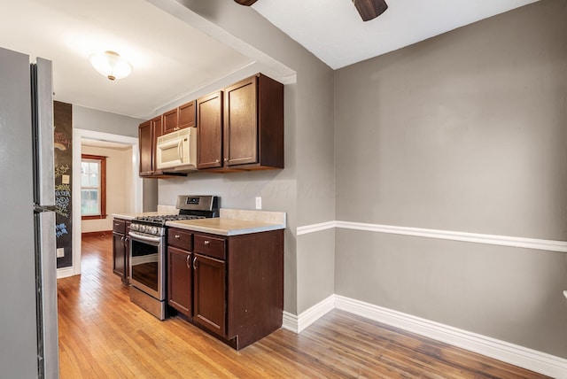 kitchen featuring baseboards, ceiling fan, light wood-type flooring, light countertops, and stainless steel appliances
