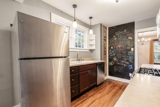 kitchen featuring dark brown cabinets, light countertops, a sink, light wood-style flooring, and stainless steel appliances