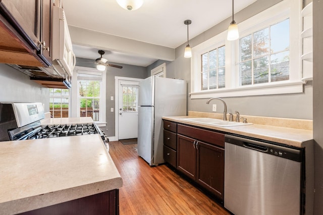 kitchen featuring dark brown cabinetry, appliances with stainless steel finishes, light wood-type flooring, a sink, and light countertops