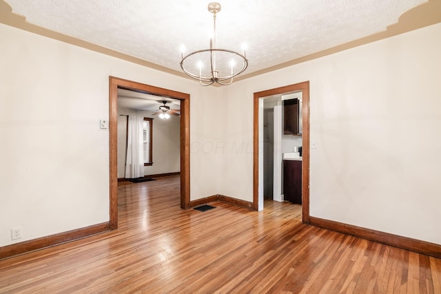 empty room with visible vents, baseboards, light wood-style floors, a textured ceiling, and a chandelier