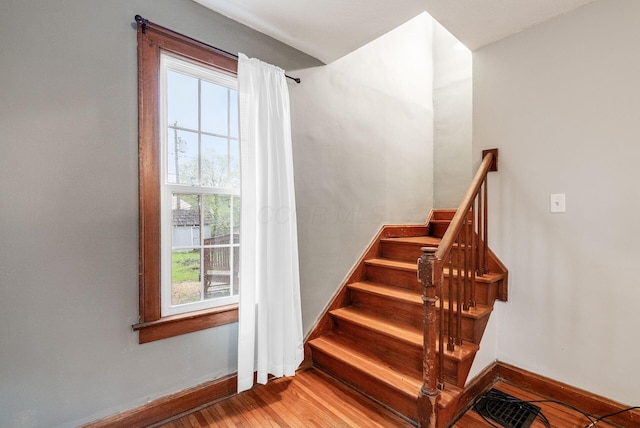 stairway featuring plenty of natural light, baseboards, and wood finished floors