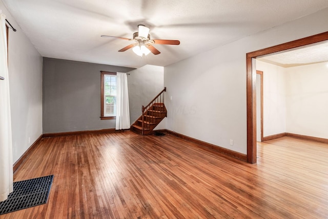 interior space featuring baseboards, ceiling fan, wood-type flooring, and visible vents