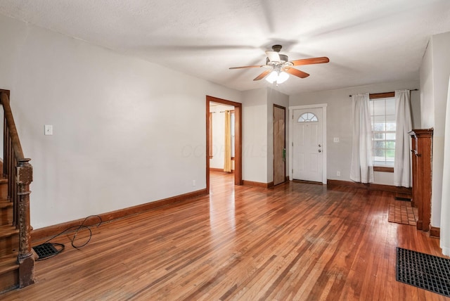 entryway with stairs, a ceiling fan, baseboards, and light wood-style flooring