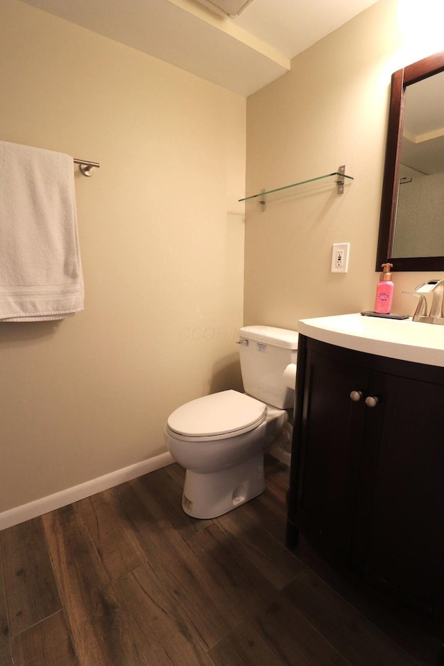bathroom with vanity, baseboards, wood finished floors, and toilet