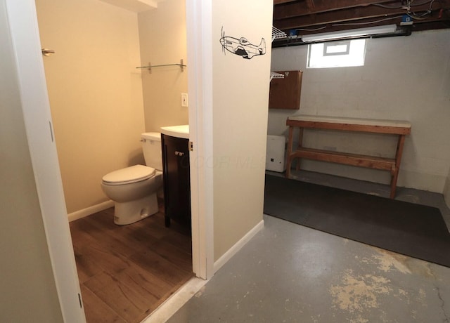bathroom featuring vanity, baseboards, concrete flooring, and toilet