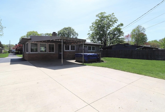 rear view of property featuring a lawn, a patio area, fence, and a chimney