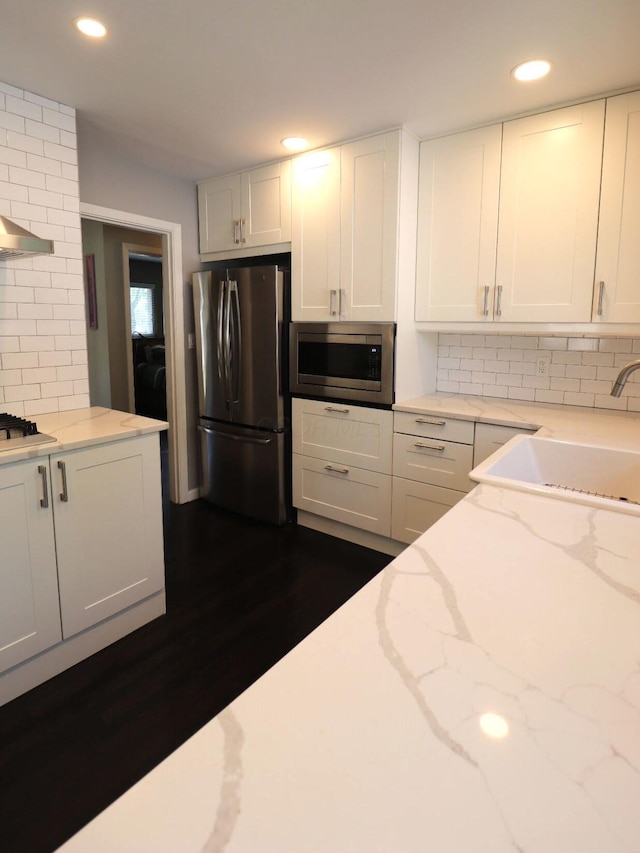 kitchen featuring recessed lighting, white cabinets, a sink, backsplash, and stainless steel appliances