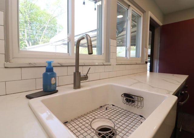 details with a sink, light stone counters, and decorative backsplash