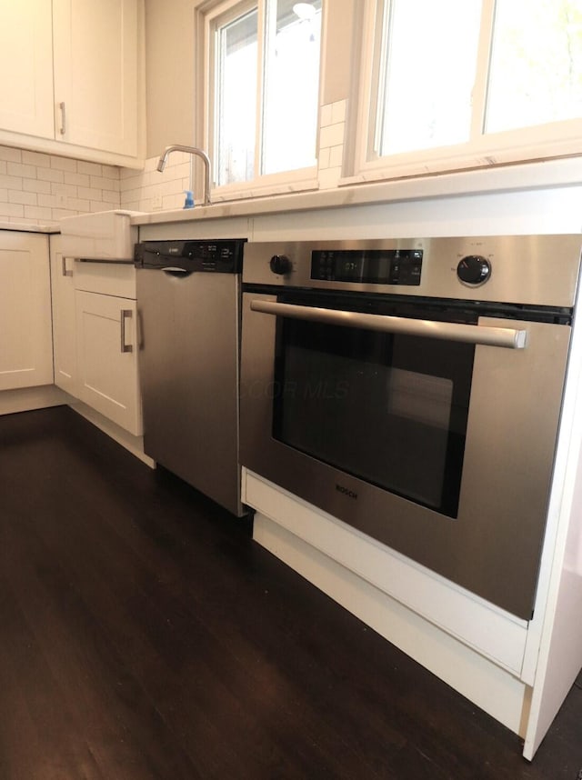 kitchen with dark wood-type flooring, light countertops, appliances with stainless steel finishes, and white cabinets