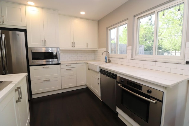 kitchen with recessed lighting, white cabinetry, light stone counters, a sink, and appliances with stainless steel finishes