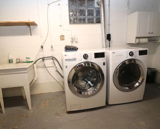 clothes washing area with laundry area, washing machine and dryer, and concrete block wall
