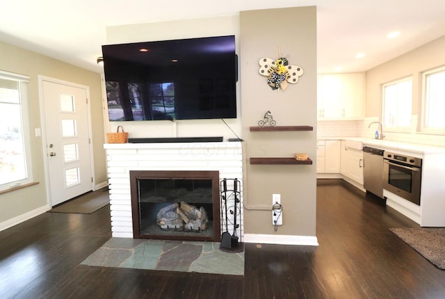 living area with recessed lighting, baseboards, dark wood-style flooring, and a fireplace with flush hearth