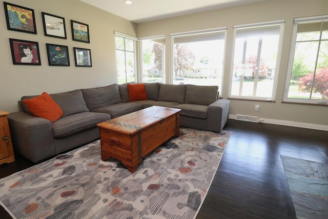 living area featuring dark wood-style flooring, baseboards, visible vents, and a wealth of natural light