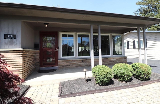 property entrance with a porch and brick siding