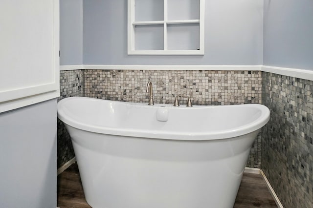 full bath with a freestanding bath, wainscoting, and wood finished floors