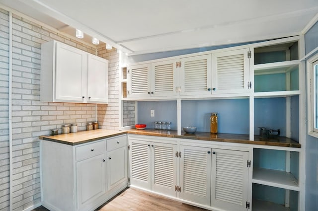 kitchen featuring white cabinets, open shelves, wood counters, and brick wall