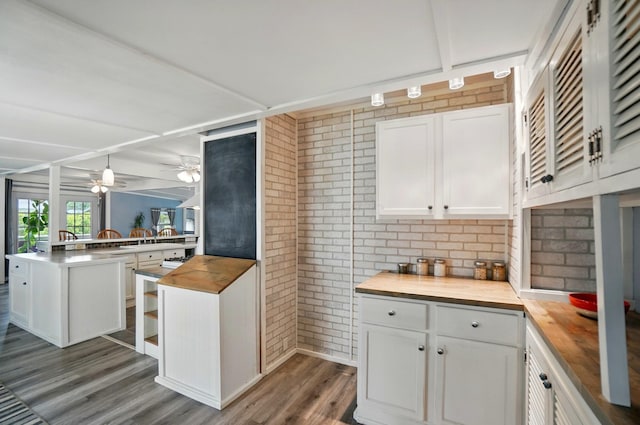 kitchen with a ceiling fan, brick wall, wood finished floors, white cabinets, and butcher block countertops