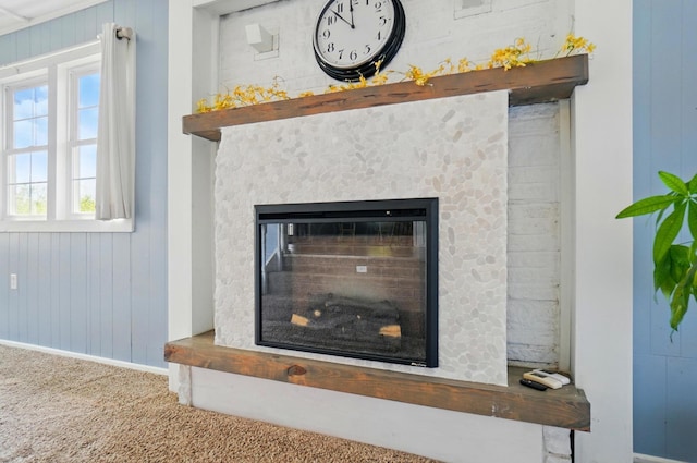 room details with carpet flooring, wooden walls, baseboards, and a glass covered fireplace