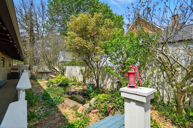 view of yard featuring a fenced backyard and a garden pond