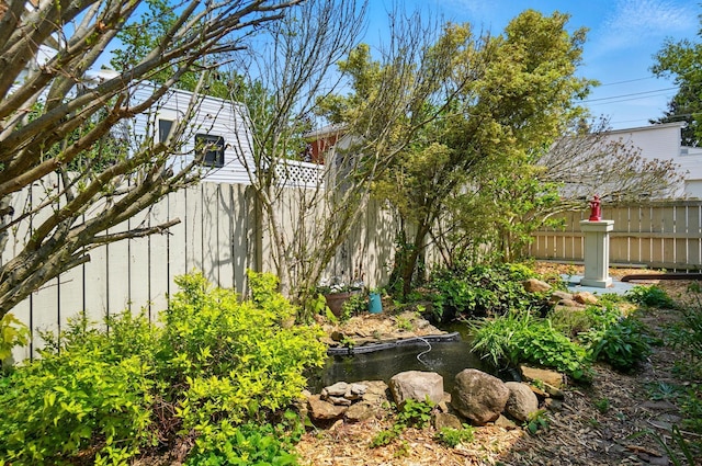view of yard featuring a garden pond and fence