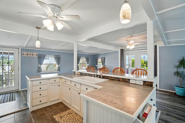 kitchen with a ceiling fan, decorative light fixtures, beam ceiling, a sink, and white cabinets