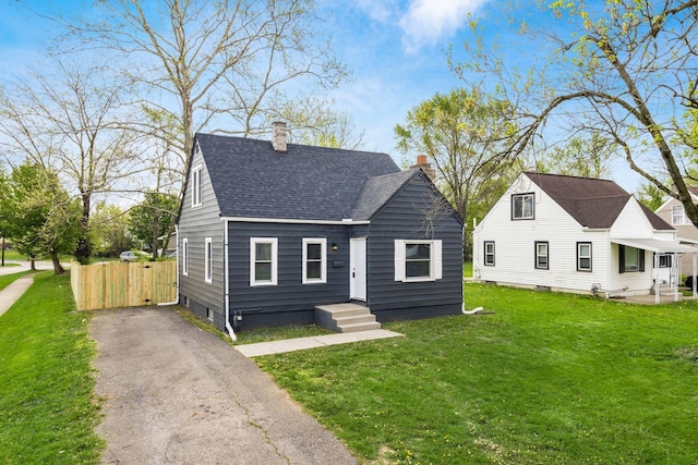 bungalow-style house featuring a shingled roof, fence, a front yard, and a chimney