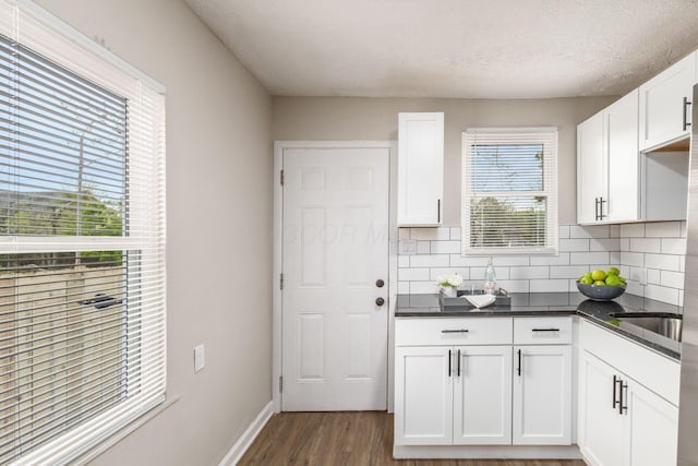 kitchen with baseboards, a textured ceiling, white cabinetry, dark wood finished floors, and backsplash