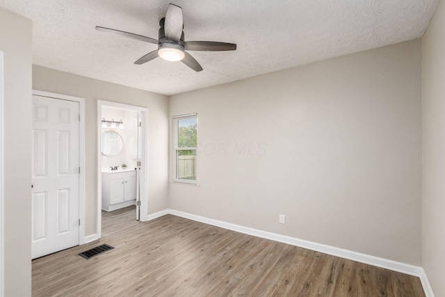 unfurnished bedroom featuring baseboards, a textured ceiling, and light wood finished floors