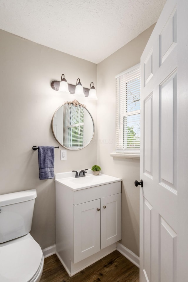 half bathroom with baseboards, toilet, and wood finished floors