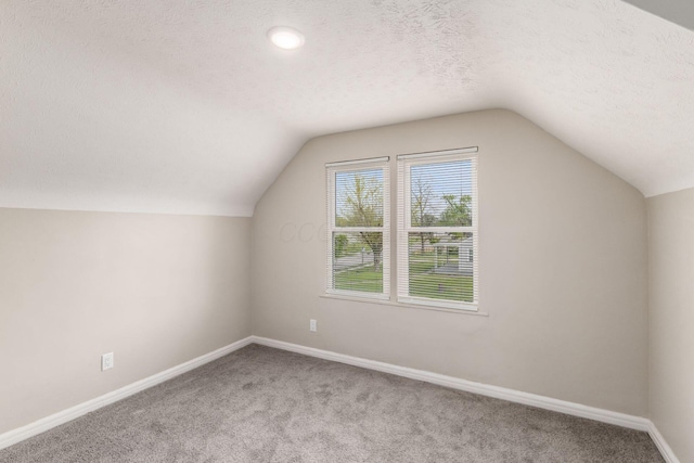 bonus room featuring a textured ceiling, vaulted ceiling, and carpet