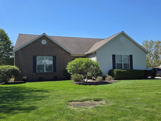ranch-style house featuring a front yard, roof with shingles, and brick siding