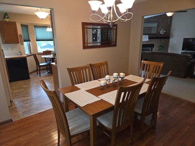 dining space with a fireplace, an inviting chandelier, and wood-type flooring